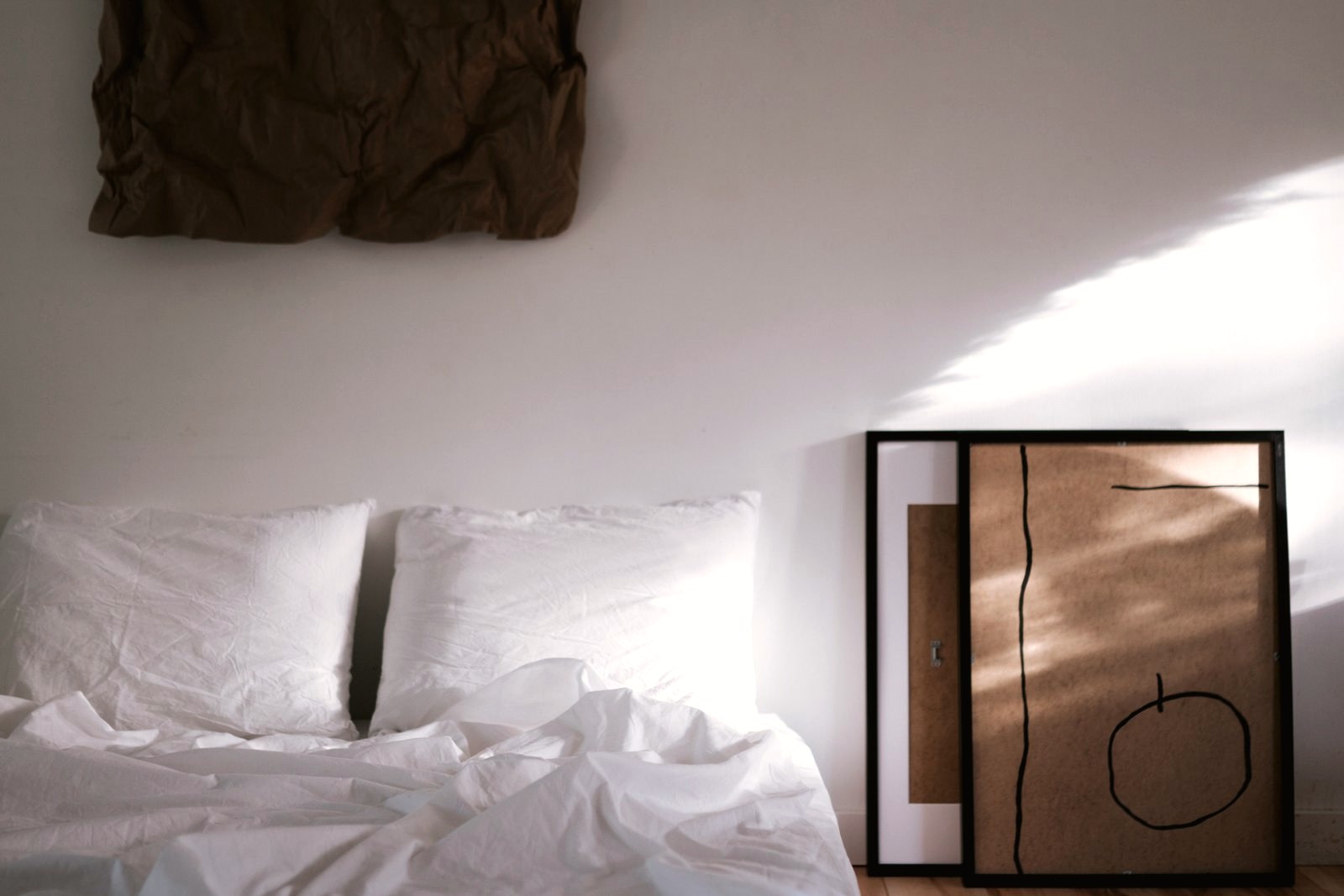 Letto in lino chiaro, con la luce del mattino che taglia la parete